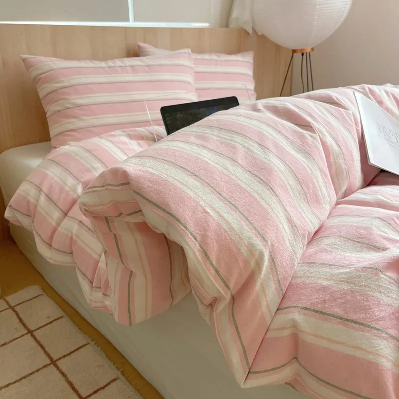 Pink and white striped cotton bedding set on a modern wooden bed