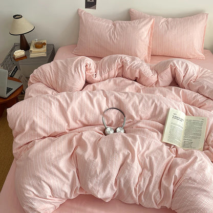 Blush Pink pinstripe bedding set styled on a bed with matching pillows