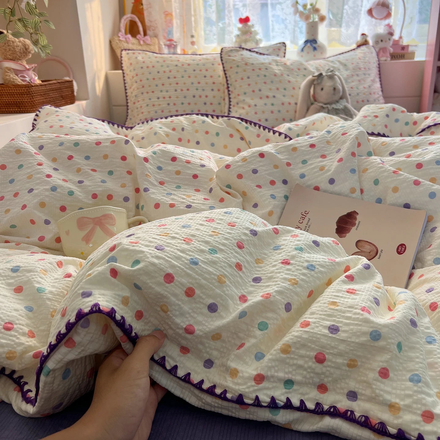 Cream Confetti Dot polka dot bedding set with purple braided trim styled on a bed