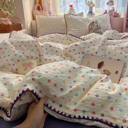 Cream Confetti Dot polka dot bedding set with purple braided trim styled on a bed