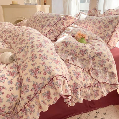 Blush Rose floral ruffle bedding set with burgundy trim styled on a bed
