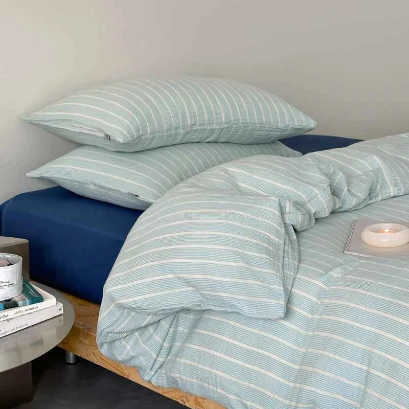 Close-up of mint striped cotton pillowcases against a navy sheet