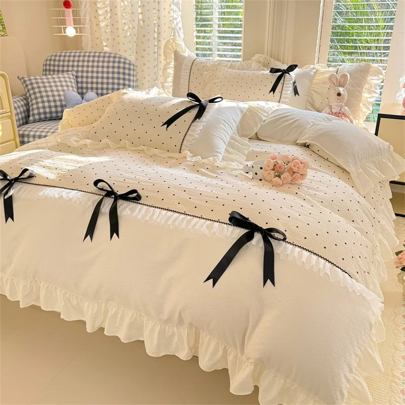 Cream Dot ruffle bedding set with black polka dots and satin bows styled on a bed