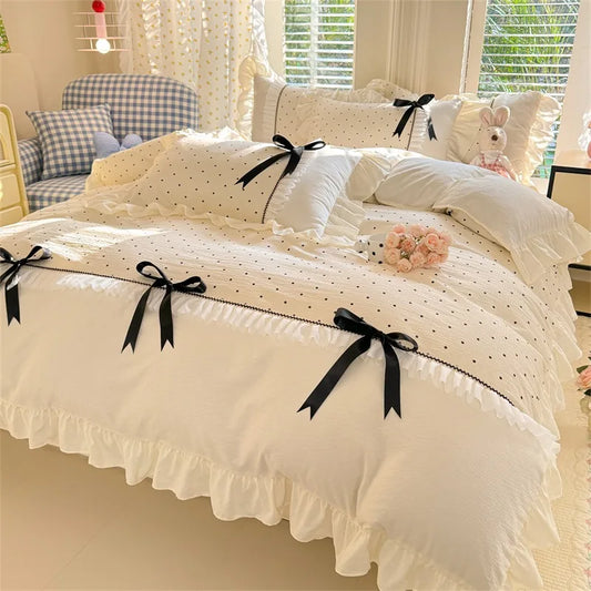 Cream Dot ruffle bedding set with black polka dots and satin bows styled on a bed