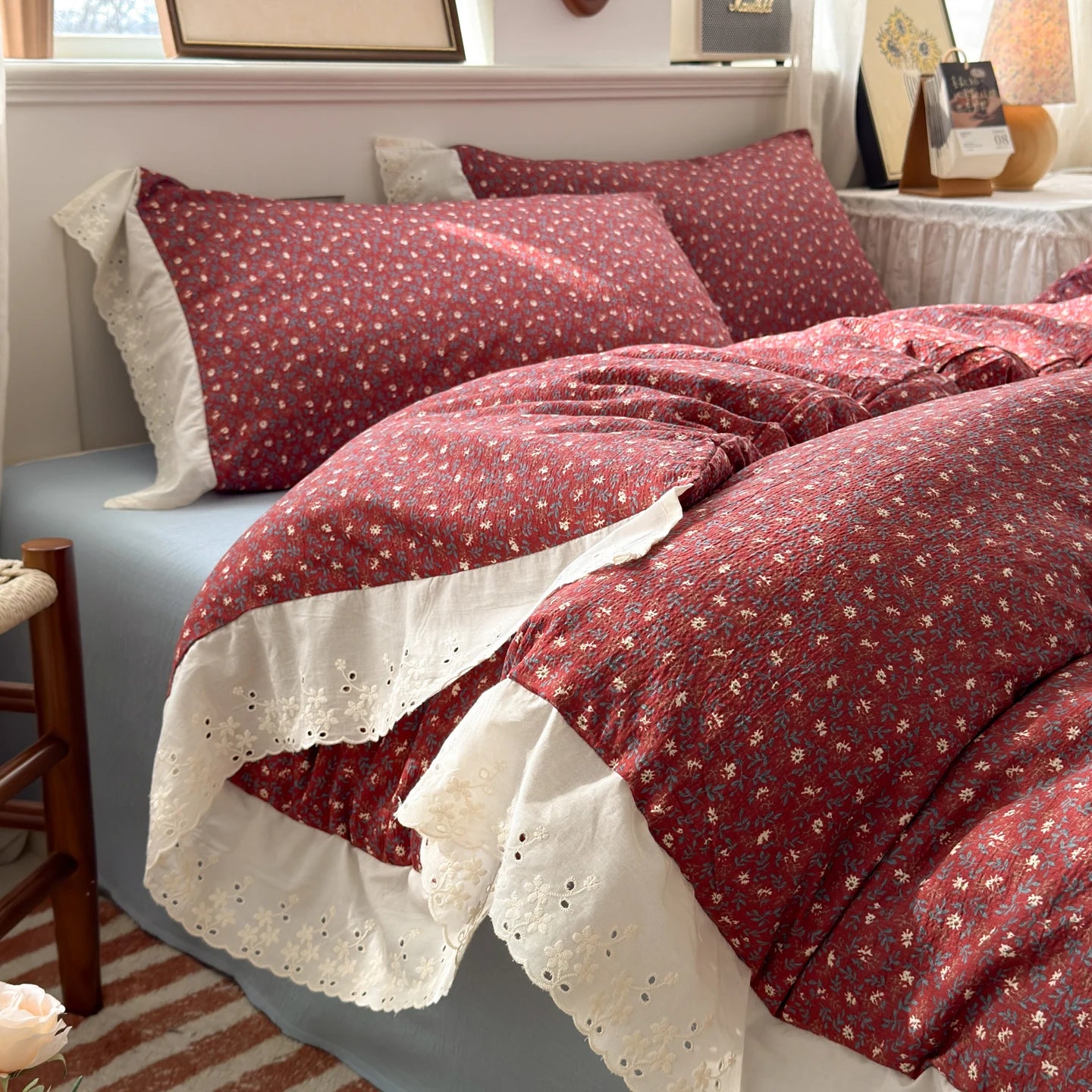 Burgundy Bloom floral ruffle bedding set with white lace trim styled on a bed