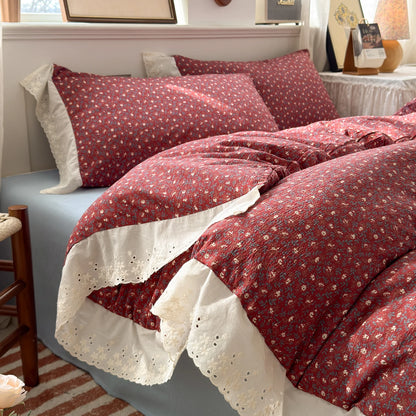 Burgundy Bloom floral ruffle bedding set with white lace trim styled on a bed