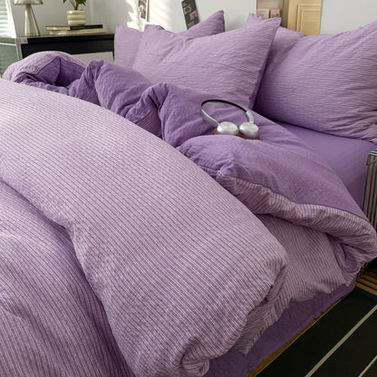 Lilac textured stripe bedding set styled on a bed with matching pillows