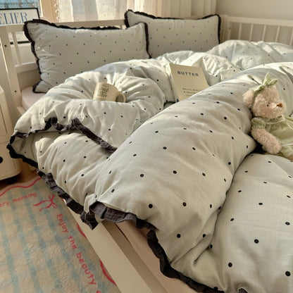 Sage green polka dot bedding set with dark ruffle trim in a bright cottage bedroom