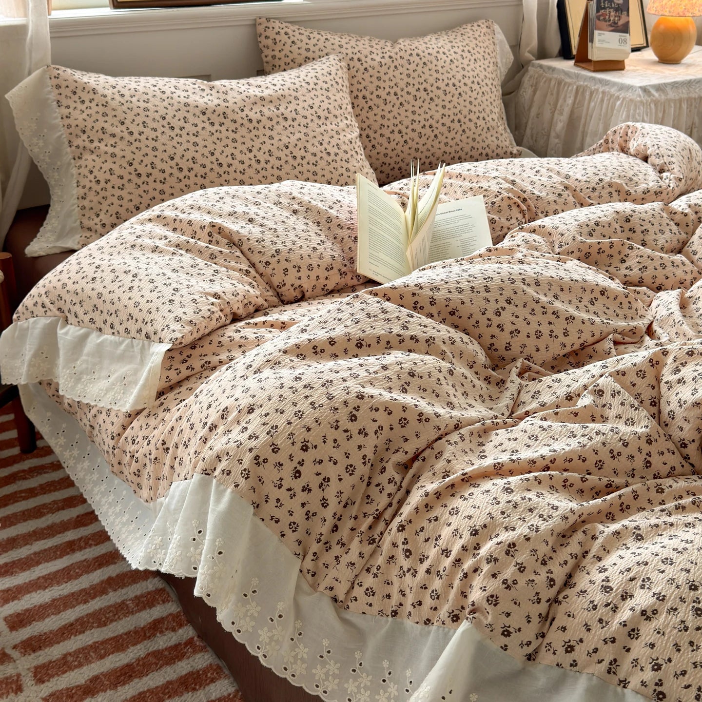 Almond Rose floral ruffle bedding set with white lace trim styled on a bed