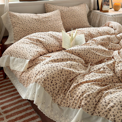 Almond Rose floral ruffle bedding set with white lace trim styled on a bed