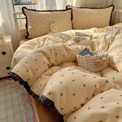 Cream bow print bedding set with dark charcoal ruffle trim in a sunlit bedroom