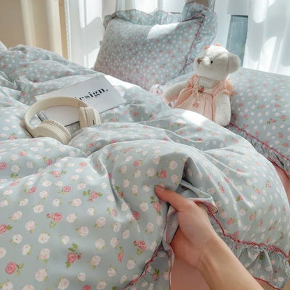 Sky Rosebud floral ruffle bedding set in blue with pink trim styled on a bed