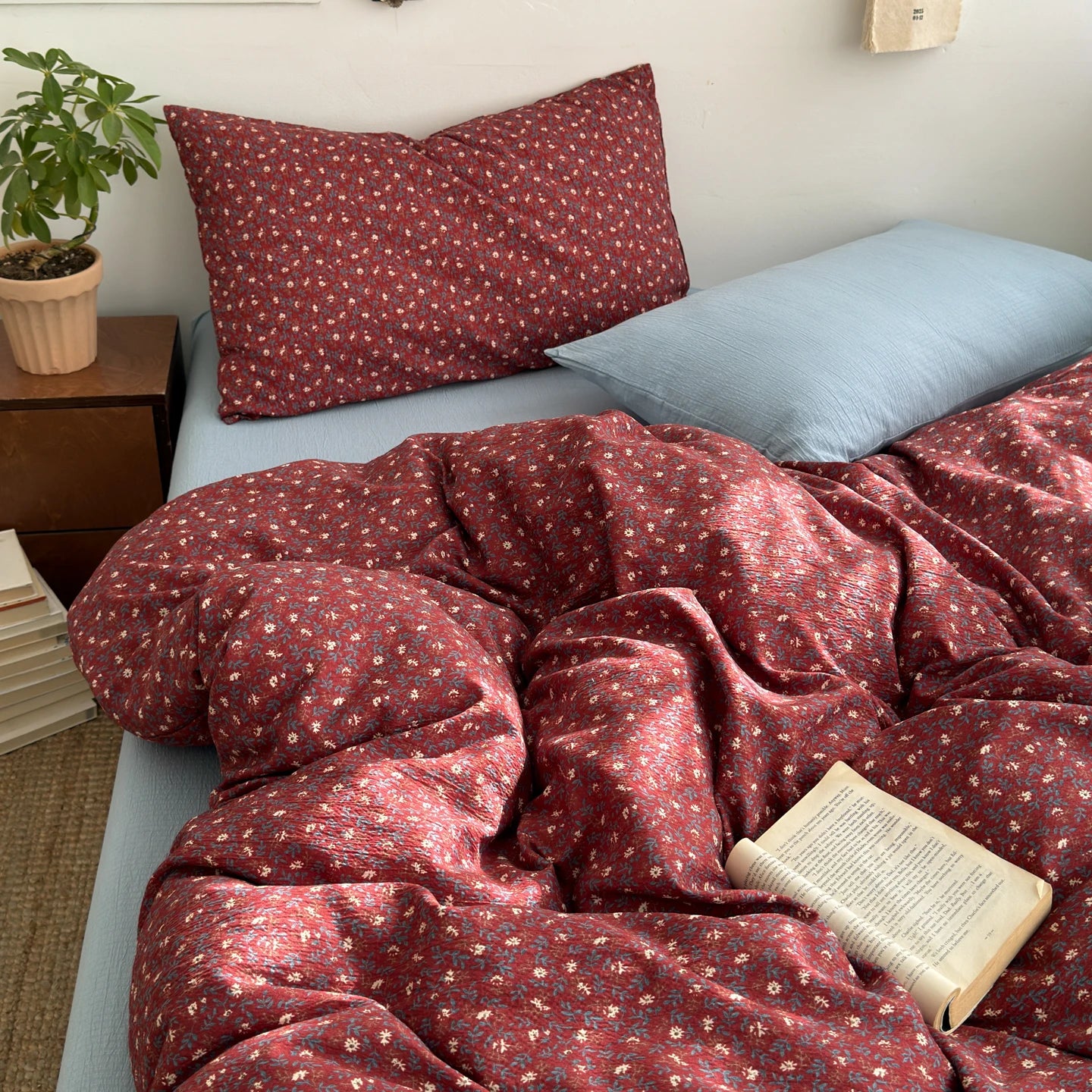Cranberry Bloom ditsy floral bedding set with solid blue pillow styled on a bed