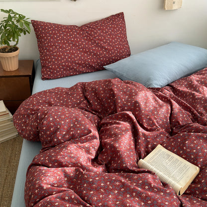 Cranberry Bloom ditsy floral bedding set with solid blue pillow styled on a bed