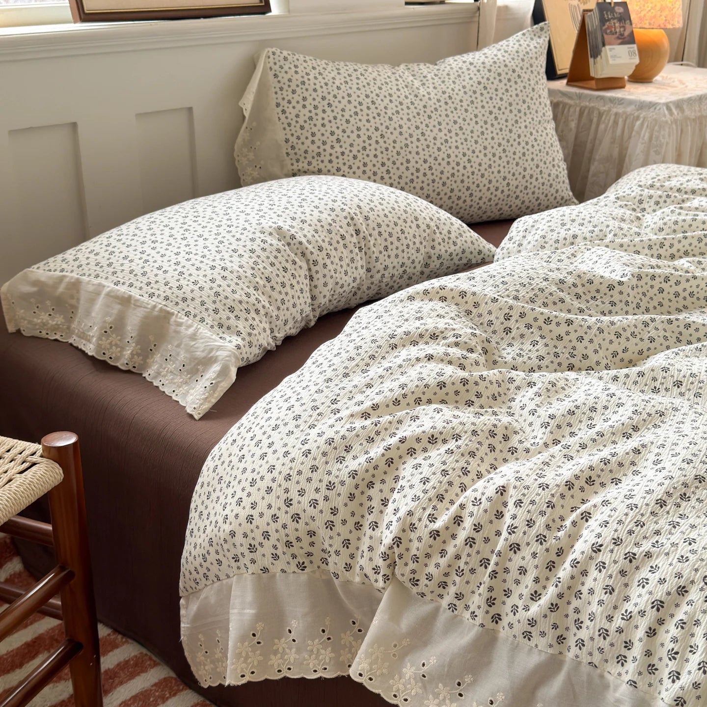 Ivory Sprig floral ruffle bedding set with white lace trim styled on a bed