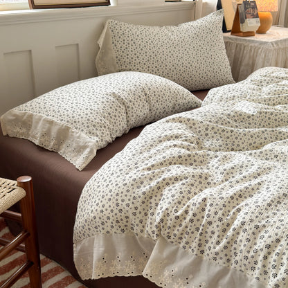 Ivory Sprig floral ruffle bedding set with white lace trim styled on a bed