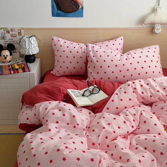 Pink Red Star print bedding set with solid red reverse styled on a bed