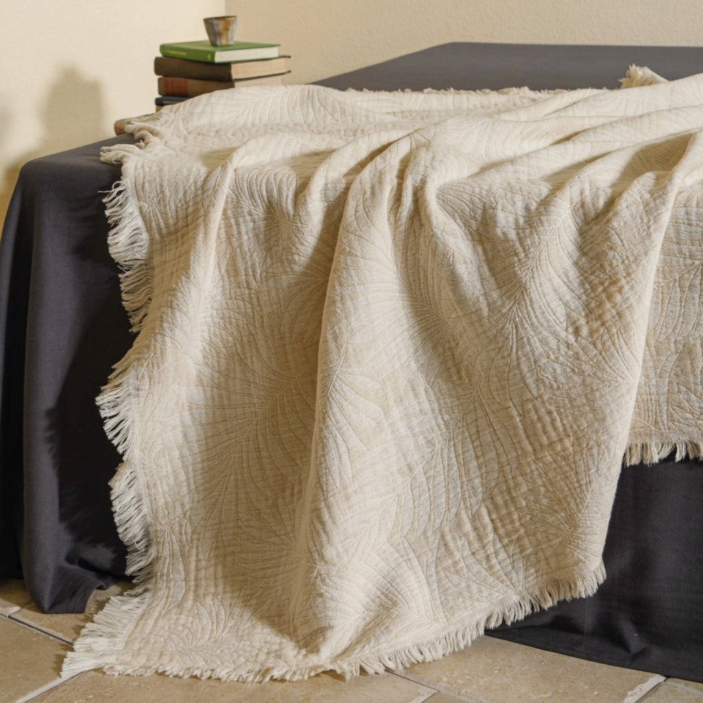 Palma Leaf Jacquard Fringed Throw Blanket - ivory leaf jacquard throw folded on a stool - WhisperLinens