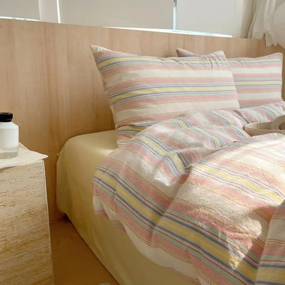 Cream bedding set with pastel stripes in pink, yellow, blue, and lavender for a soft colorful bedroom look