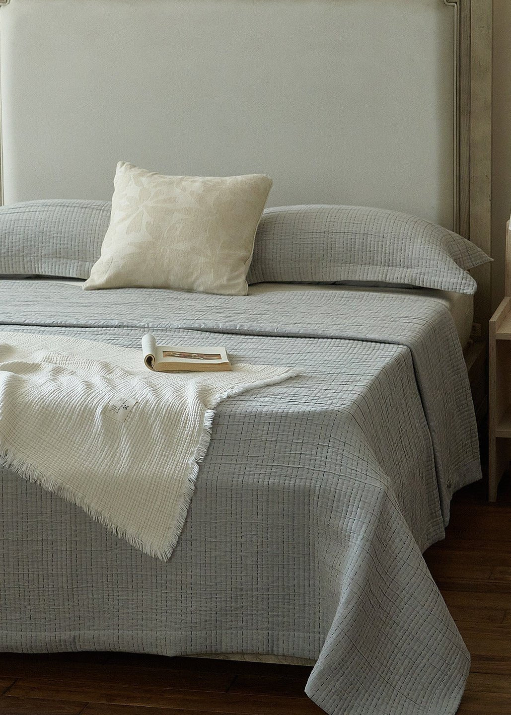 Elowen Crinkle Jacquard Throw Blanket - ivory throw on a gray quilted bed - WhisperLinens