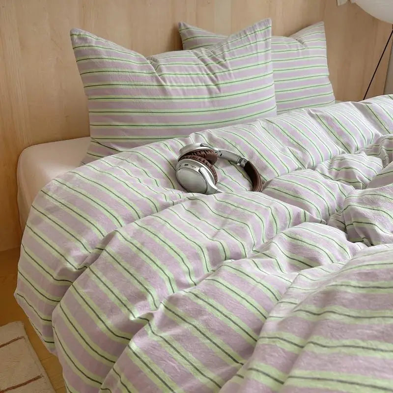Lavender bedding set with green and white stripes in a cozy minimalist bedroom