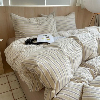 Beige cotton bedding with thin olive and gray stripes on a cozy modern bed with sunlight
