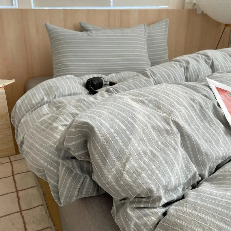 Neutral grey striped cotton bedding set with soft white lines and modern pillow shams on a cozy bed