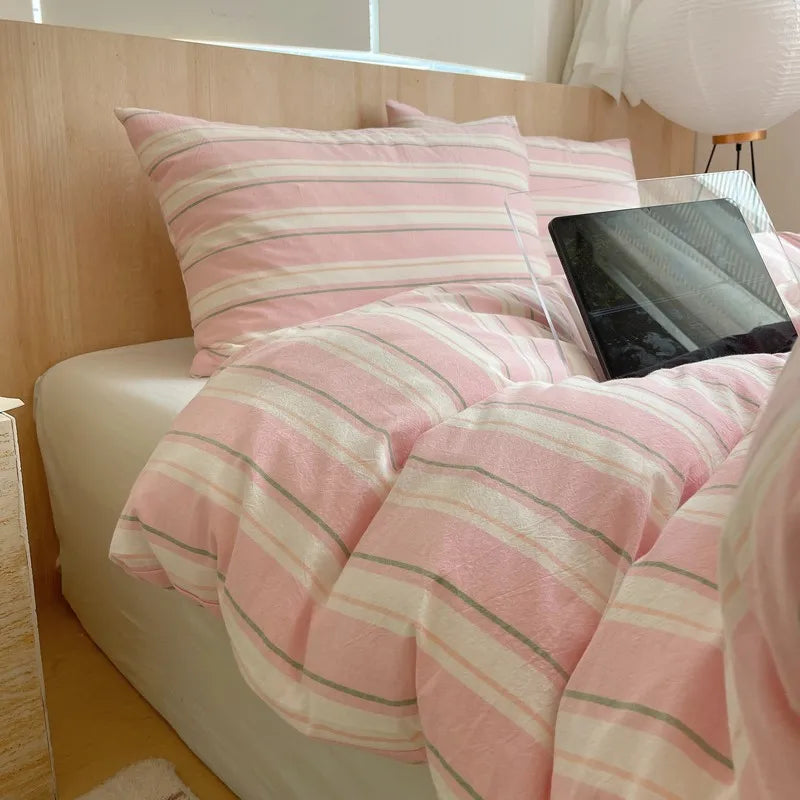Pink and white striped cotton bedding set on a modern wooden bed
