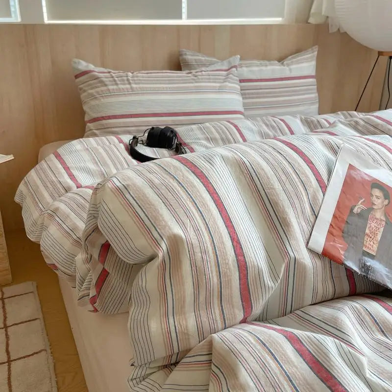 Beige cotton bedding set with red and blue striped pattern on a modern bed