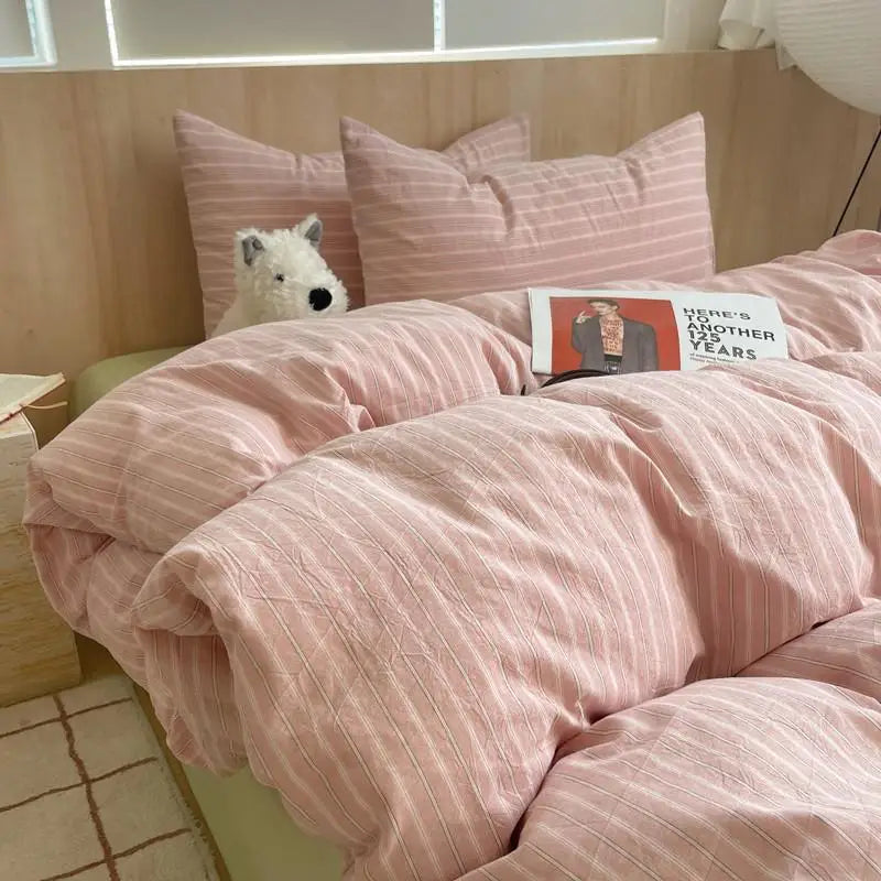 Warm rose pink striped cotton bedding set with soft pillowcases and a cozy duvet on a wooden bed