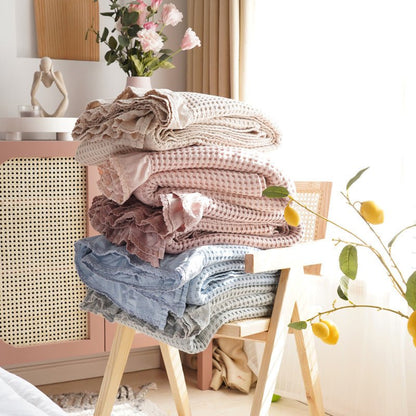 Juniper Ruffled Waffle Throw Blanket - folded throws in all five shades stacked on a stool - WhisperLinens
