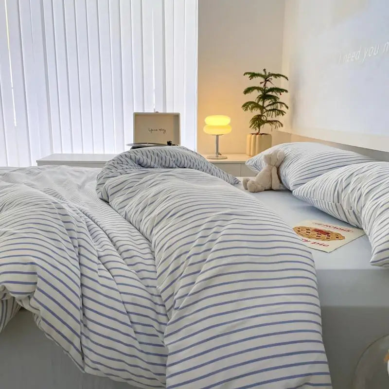 white bedding set with blue stripes on bed